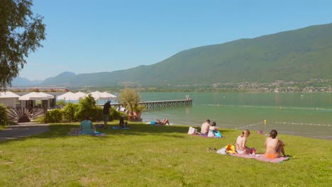 profile view of tourists sunbathing at "lac du bourget" (bourget lake), the biggest natural lake in aix-les-bains, france. 4k.