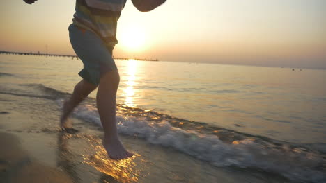 Barfüßiges-Kind,-Das-Bei-Sonnenuntergang-Im-Meerwasser-Läuft