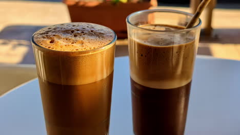 two greek frappes in summer sunlight