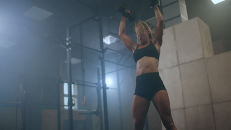 a woman raises dumbbells over her head during a workout. weight lifting. heavy training in the gym.