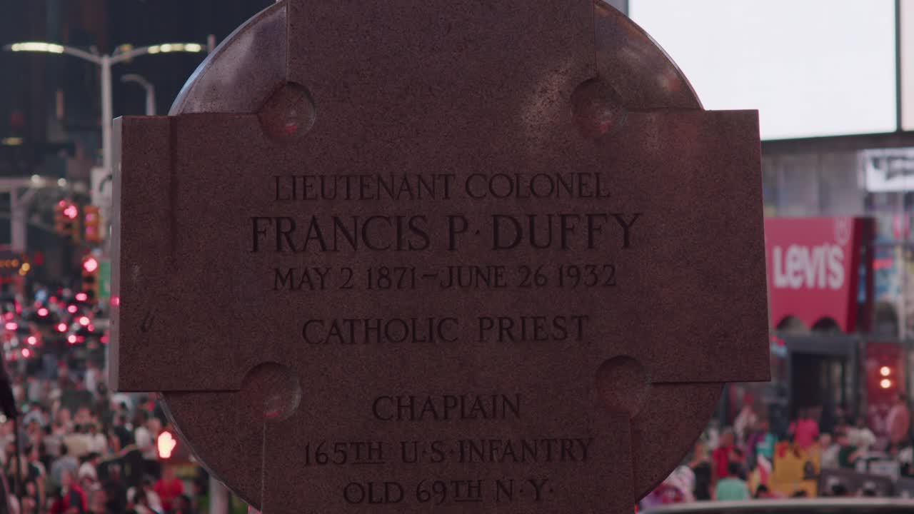 Francis P. Duffy statue in Times Square surrounded by city lights and crowds at night