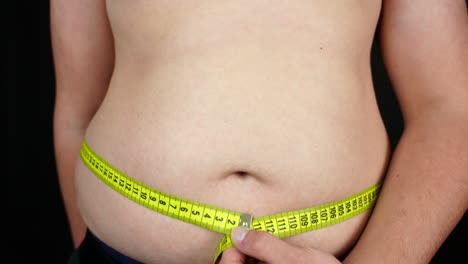 overweight teenager measuring his belly with meter, close up