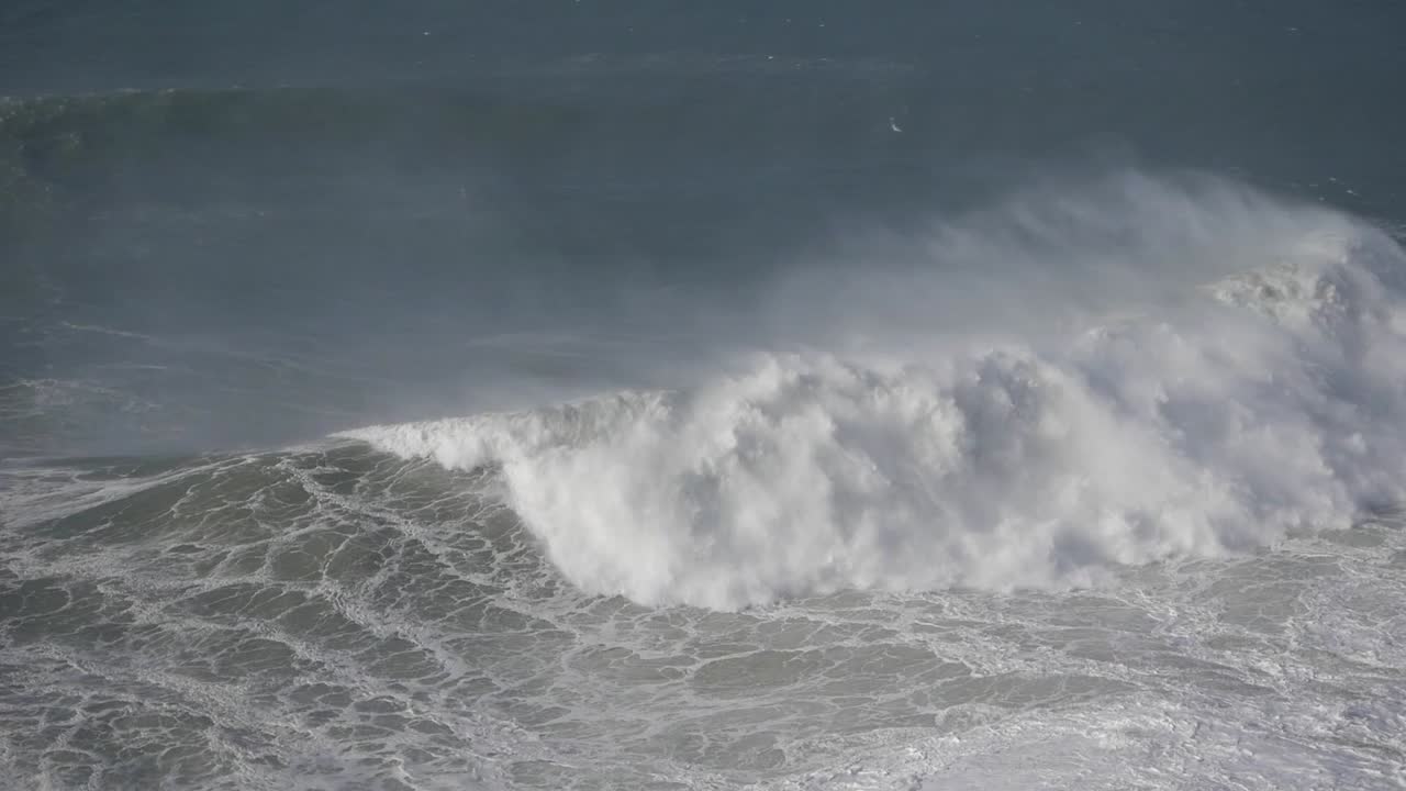 Massive waves crash with power and spray in Nazaré, Portugal, showcasing nature's force