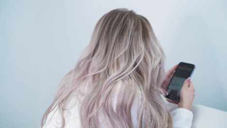 mujer navega por internet con el teléfono sometida a una depilación láser