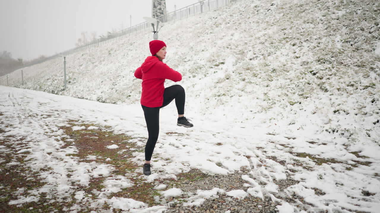 은 후디와 검은 장갑을 입고, 철 철로와 안개로 둘러싸인 눈 인 언덕에 둘러싸여 있는 여성이 눈 은 땅에서 야외에서 역동적인 겨울 운동을 하고 있습니다.