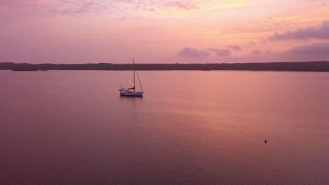 vista aérea de un velero en medio del océano con un hermoso amanecer en menorca españa, tiro amplio en órbita