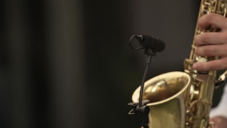 la mano del músico tocando un saxofón, enfatizando las teclas doradas y los detalles intrincados