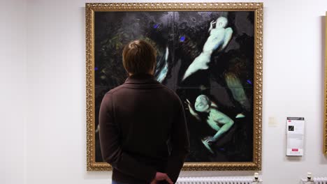 person viewing a painting of nudes