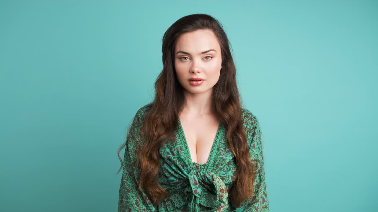 Shocked young woman covers mouth in blue studio