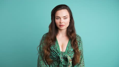 shocked young woman covers mouth in blue studio