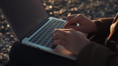 persona trabajando en una computadora portátil en la playa al atardecer
