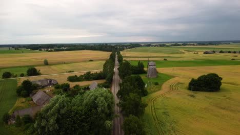 aerial shot of an old windmill in the field by the road, drone shot