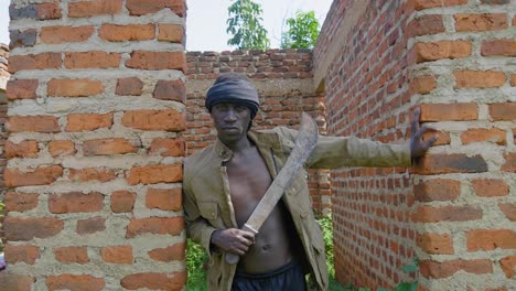 una foto de un joven gángster africano sosteniendo un machete en una casa abandonada en áfrica rural