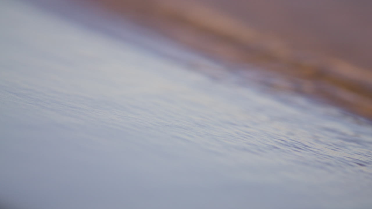 Slow motion close-up of gentle waves on a serene sandy beach