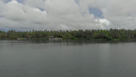 4k-Hyperlapse-Aus-Der-Luft-Eines-28-jährigen-Indischen-Mannes-In-Seinem-Urlaub,-Der-In-Den-Backwaters-Von-Varkala,-Umgeben-Von-Kokospalmen,-Ein-Kajak-Paddelt