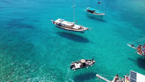 Drone-of-boats-parked-in-shallow-crystal-blue-waters-on-the-Turkish-Riviera-in-Bodrum