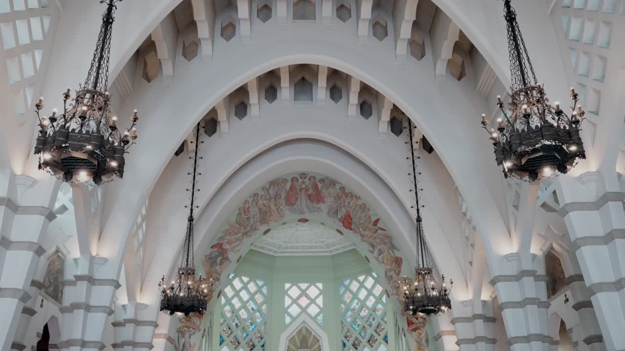 Intricate ceiling of a cathedral with arched beams and ornate chandeliers