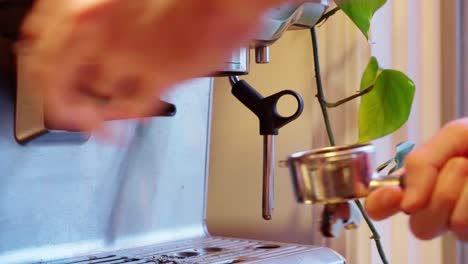 hombre caucásico barista aficionado golpeando y tirando de espresso disparado luego purgar cerca de la ventana estática apretada