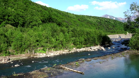 blue pond relaxing river flowing its water through rocks next to an imposing mountain of abundant green vegetation under a beautiful clear sky in a wonderful landscape in hokkaido shirogane japan