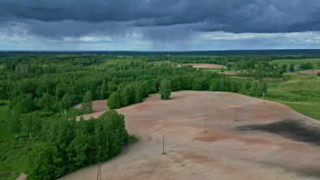 Dark-storm-clouds-flowing-above-agriculture-landscape,-aerial-view