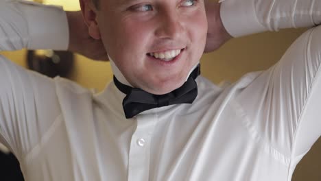 groom getting ready in a white shirt and black bow tie