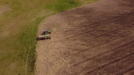 Aerial-drone-shot-of-tractor-turning-at-the-end-of-farm-field-during-plowing-process-during-sun---Agribusiness-and-Ecosystem-on-Agricultural-field
