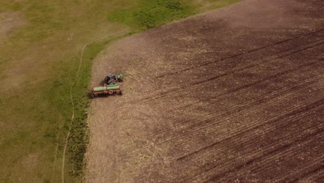 aerial drone shot of tractor turning at the end of farm field during plowing process during sun - agribusiness and ecosystem on agricultural field