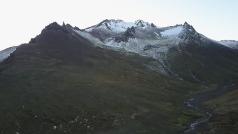 Dormant-Volcano-Covered-in-Snow-with-Scenic-Green-Landscape-from-an-Aerial-Dolly-Drone-Shot-in-Iceland