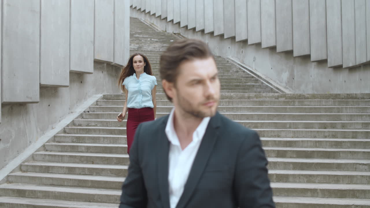 길거리에서 여자를 기다리는 사업가. 웃는 비즈니스 커플이 야외에서 이야기하고 있습니다.