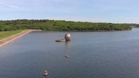 aerial flyover showing boats von bewl lake visiting draw off towers with forest in background