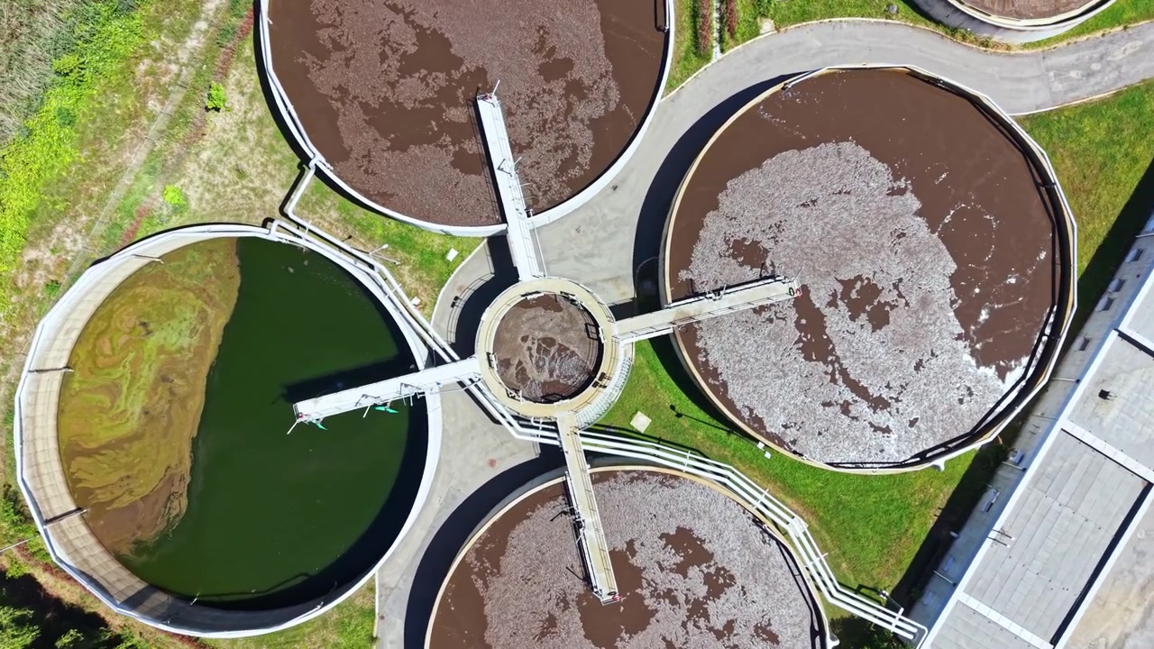 Planta de tratamiento de aguas residuales en funcionamiento durante el día mostrando procesos en múltiples tanques circulares