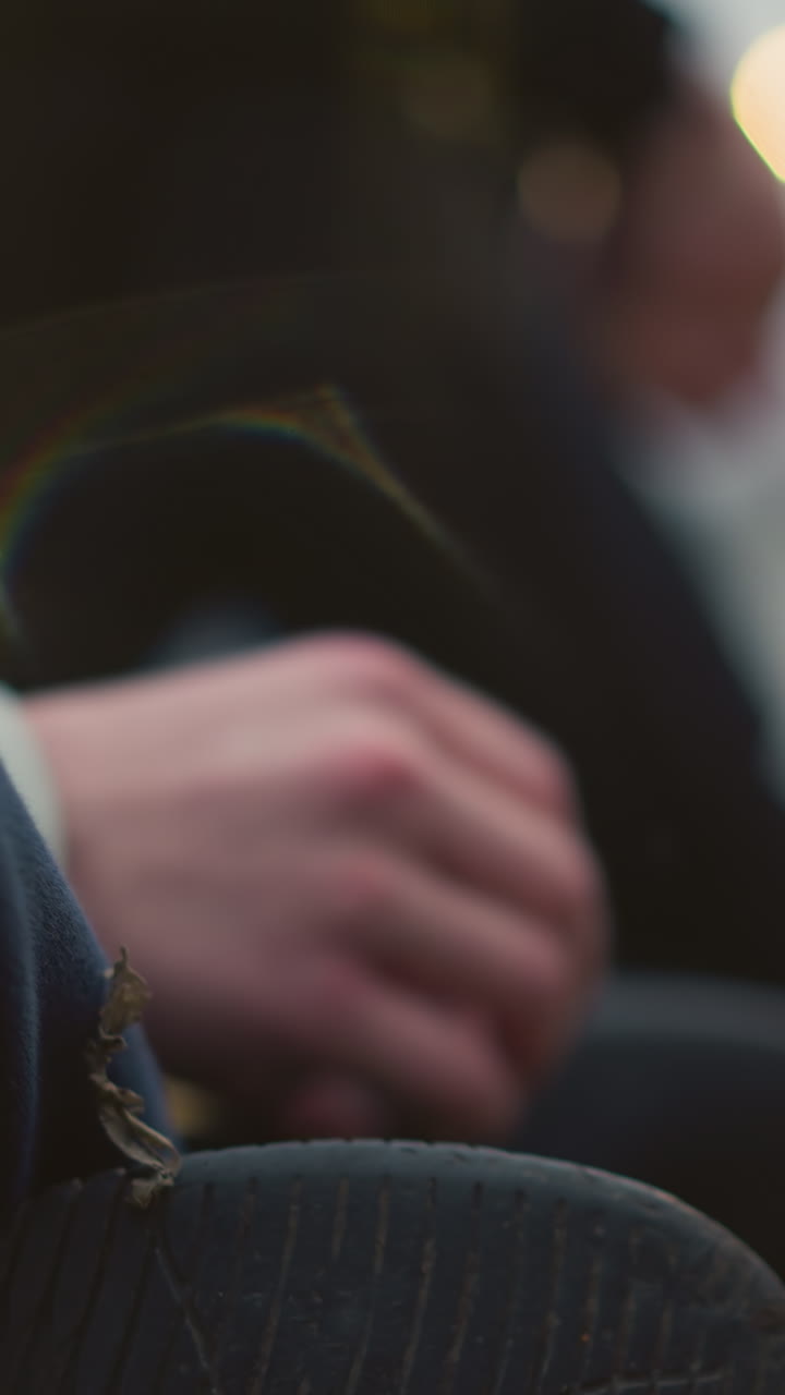 Close-up of two persons seated on the grass with light reflections and grass particles on one person's leg, with a blurred background