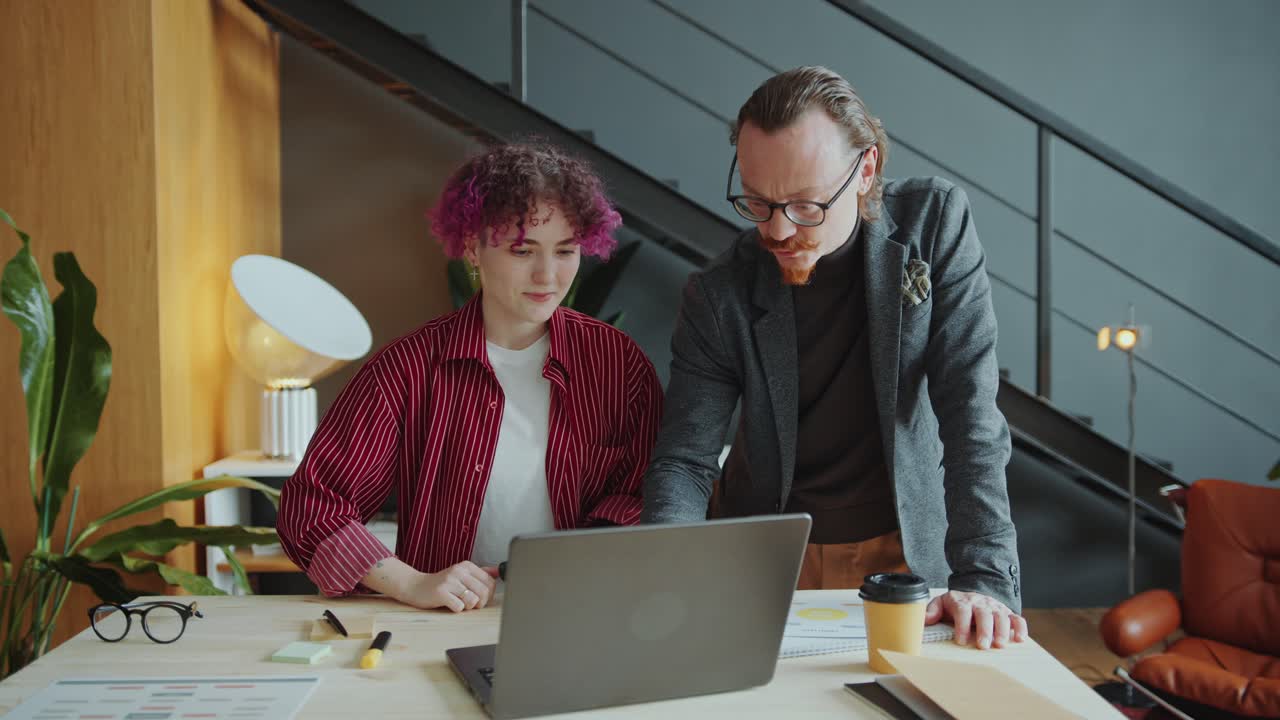 CEO Explaining Business Plan on Laptop to Female Employee with Prosthetic Arm