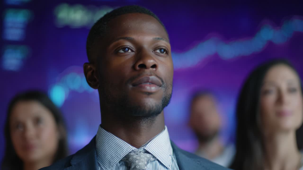 A focused and determined individual stands confidently among peers in a professional setting, illustrating ambition and leadership in a dynamic business environment with data visuals in the background