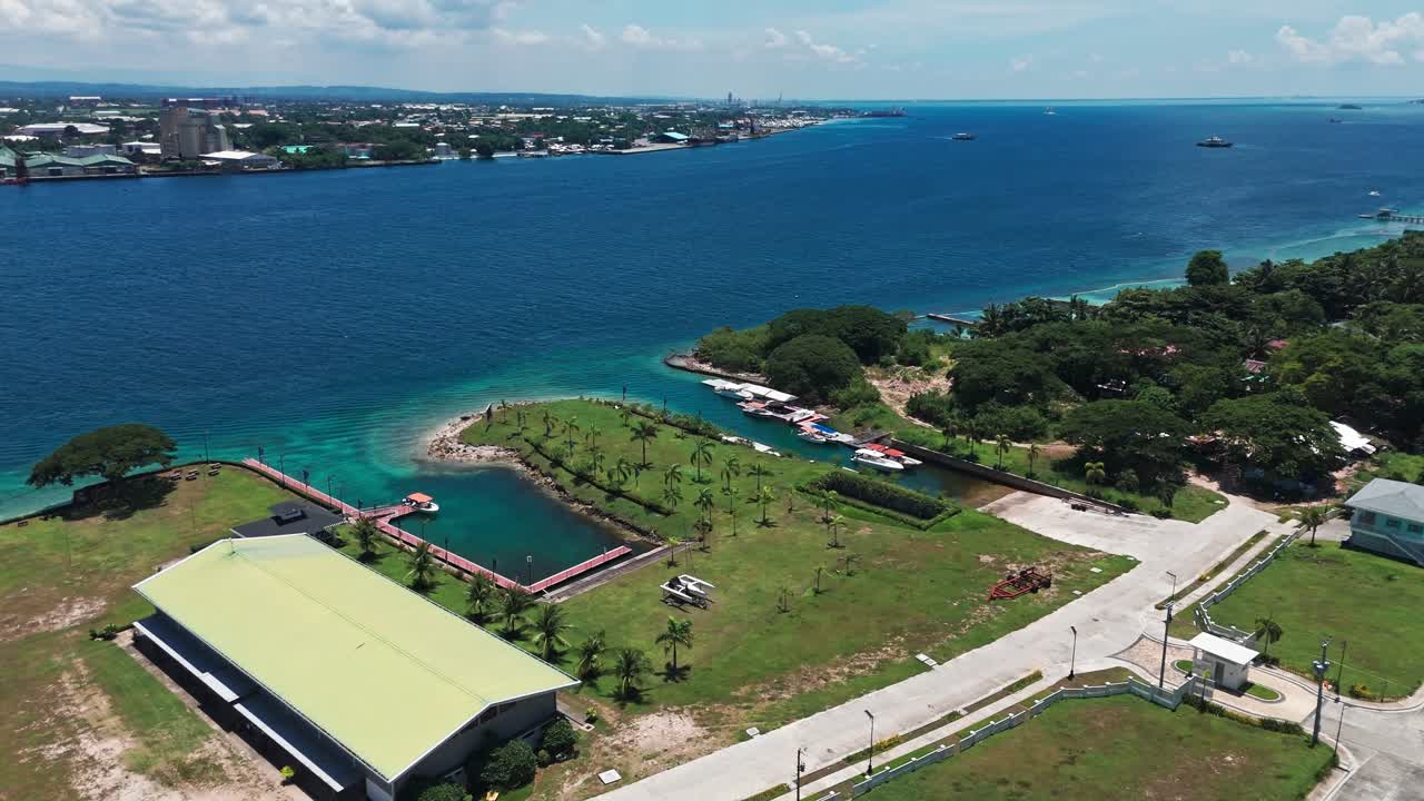 Sweeping aerial of Philippine coast with urban port, boats, marina, and green resort zone—ideal for travel, development, and infrastructure themes