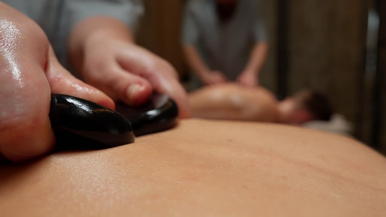 Nærbillede af hot stone massage på en kvindes ryg på et spa