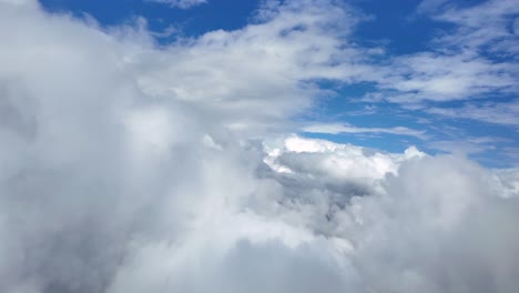 an immersive pilot’s view flying freely through some cottony stratocumulus clouds under an intense color blue sky. shot taken from a jet cockpit. ultra-realistic 4k