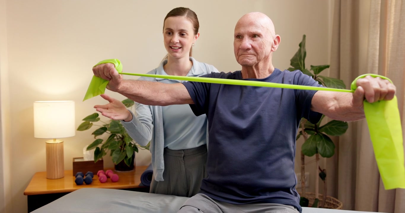 Physical Therapist Assisting Senior Man with Resistance Band Exercise