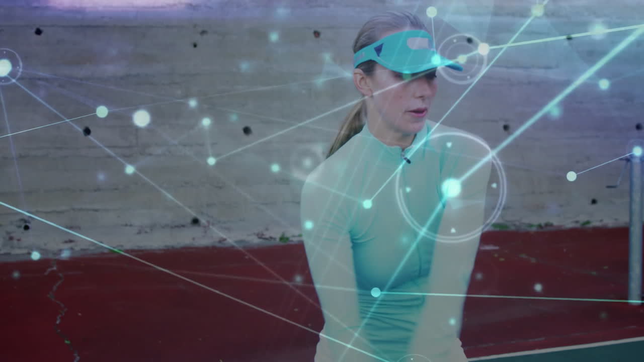 female athlete gripping racket on red hardcourt, displaying sports tech network overlay