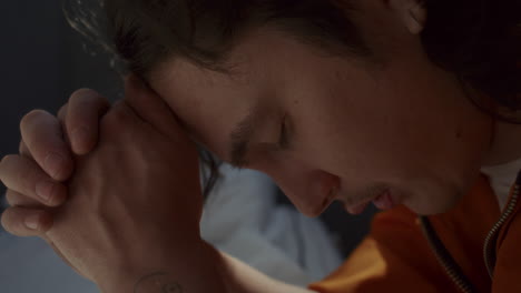 close-up of inmate praying with clasped hands and eyes closed