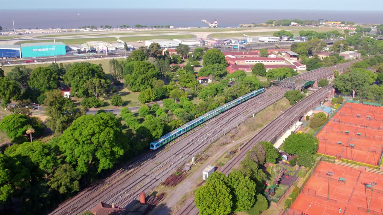 muñeca en vista aérea del tren de buenos aires, transporte urbano sostenible, pista de aterrizaje de aviones en el fondo, día soleado