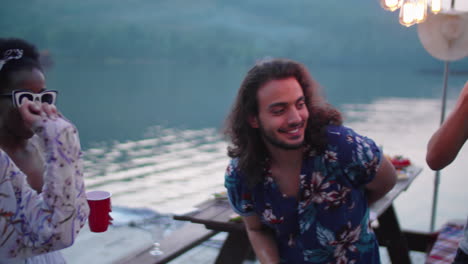 friends dancing and clinking cups in toast at lake party