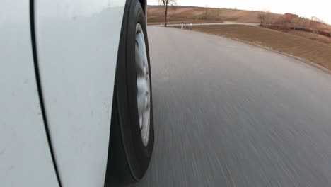 super close up, static shot of a car tire meanwhile driving down on empty roads