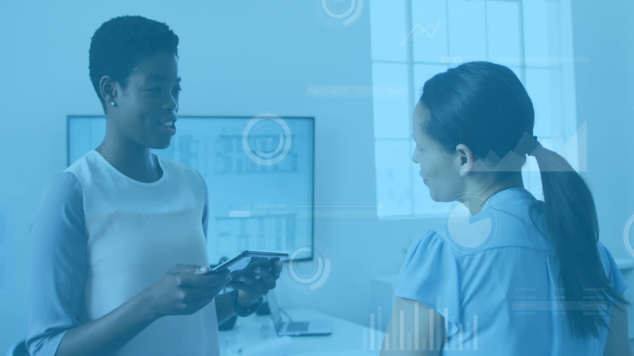 Animation of data processing over two diverse women discussing over a digital tablet at office