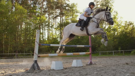 the women demonstrates skills in jumping with a horse over an obstacle in a horseclub.