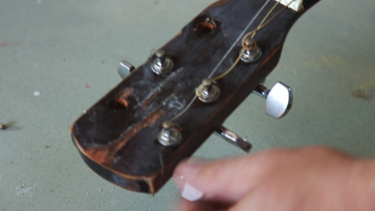 Taking off the old strings of a junky guitar
