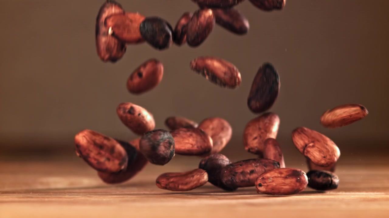 Fave di cacao crude che cadono su un tavolo di legno al rallentatore