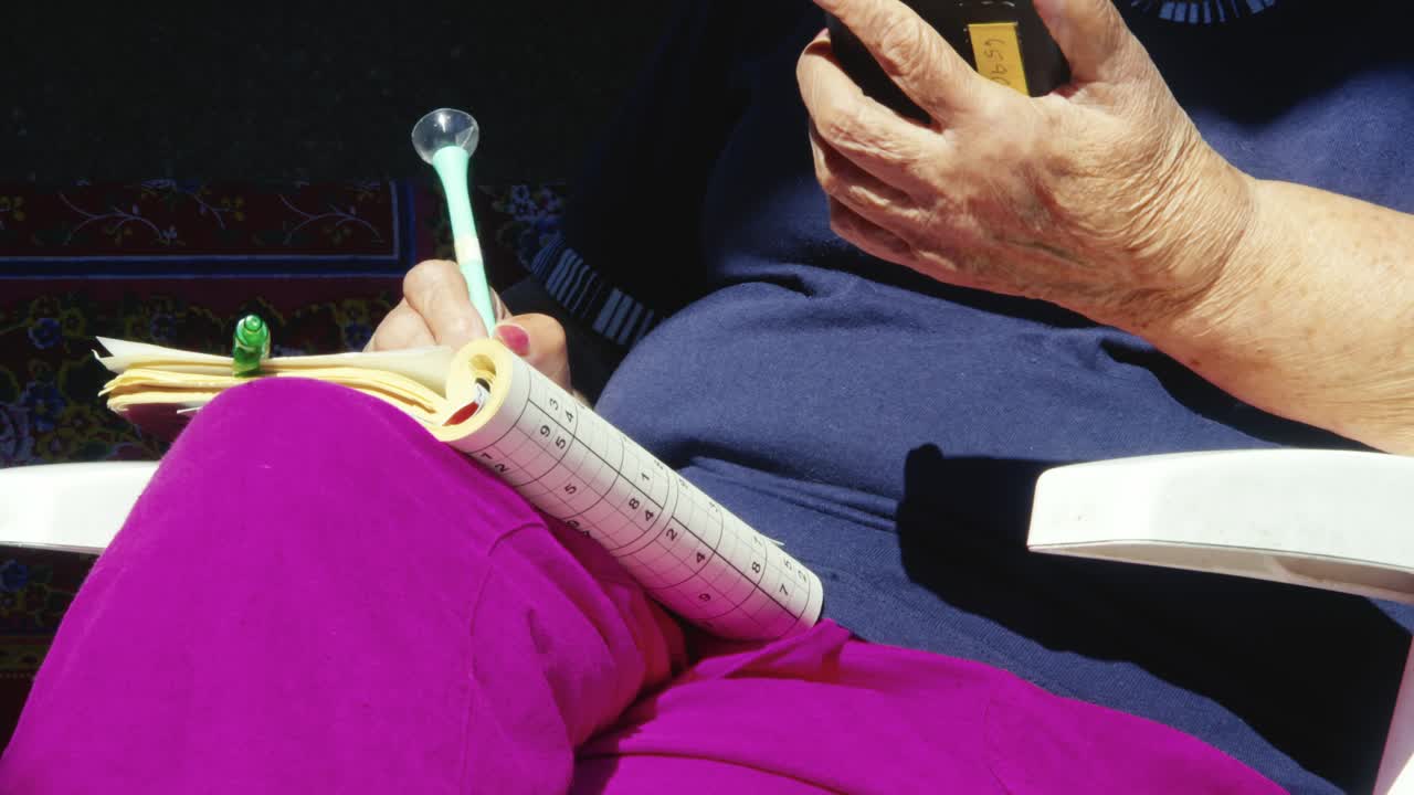 Independent woman sits outdoor with puzzle book using smart phone