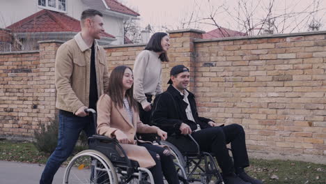 woman and man taking a walk with her disable friends in wheelchair around the city 1