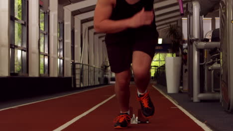 fit man running on indoor track